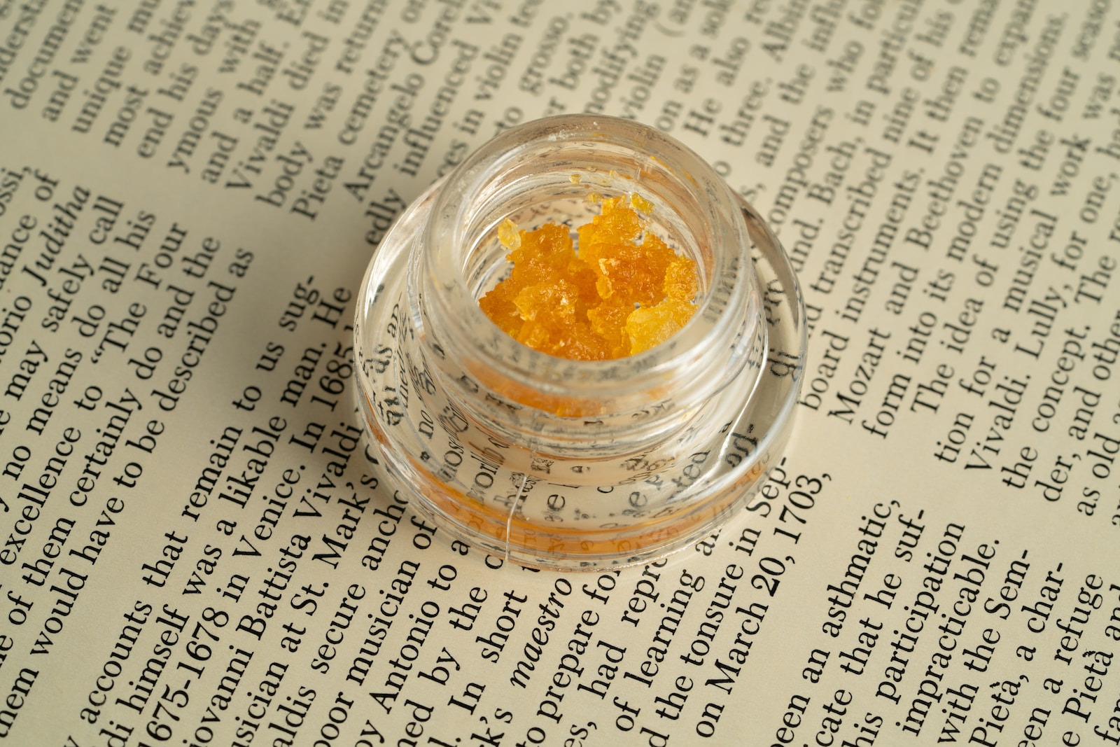 a small jar filled with yellow stuff sitting on top of a book